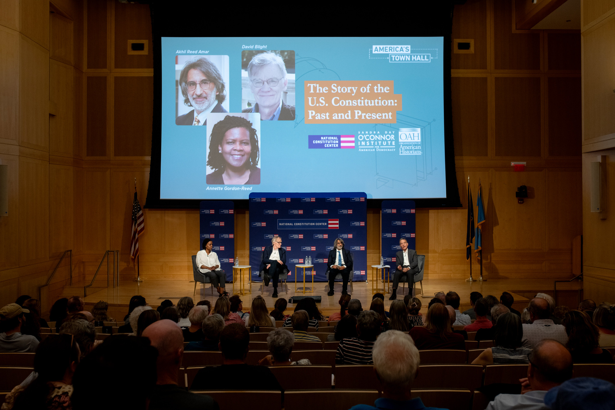 54611042785_640800f431_k A panel of four speakers sits on a stage in an auditorium with an audience watching. A large screen behind them reads, "The Story of the U.S. Constitution: Past and Present," highlighting the importance of Civics Education.