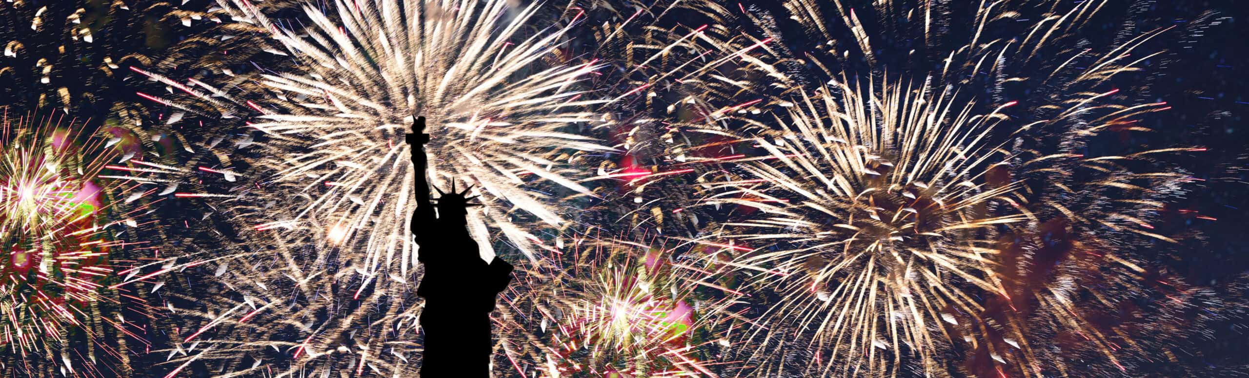 The silhouette of the Statue of Liberty stands against a night sky filled with bright, colorful fireworks bursting in celebration of America's 250th Anniversary.