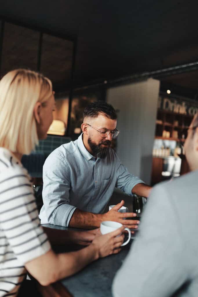 Smiling young businessman going over paperwork with his colleagues during a casual meeting in the lounge area of an office