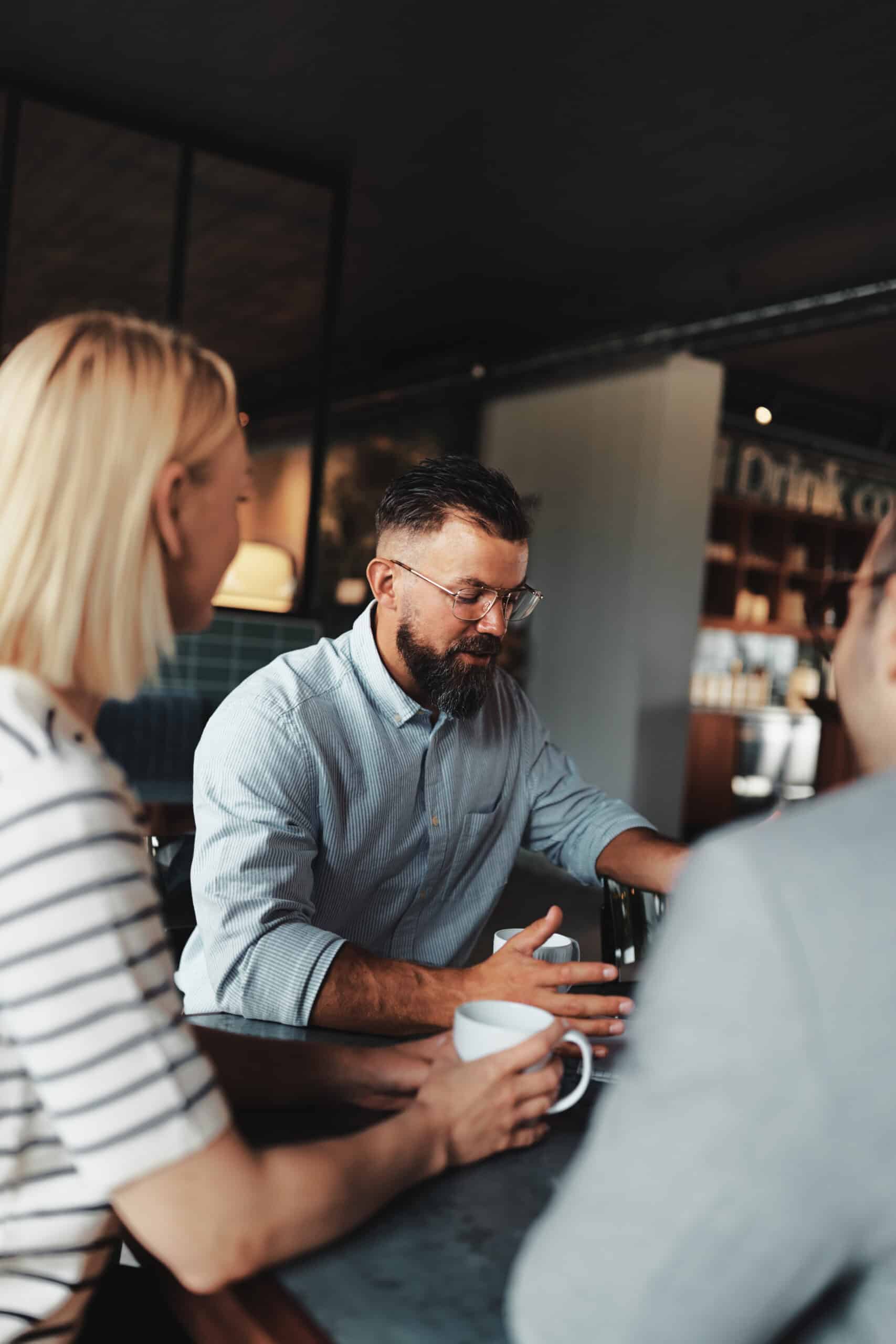 Smiling young businessman going over paperwork with his colleagues during a casual meeting in the lounge area of an office