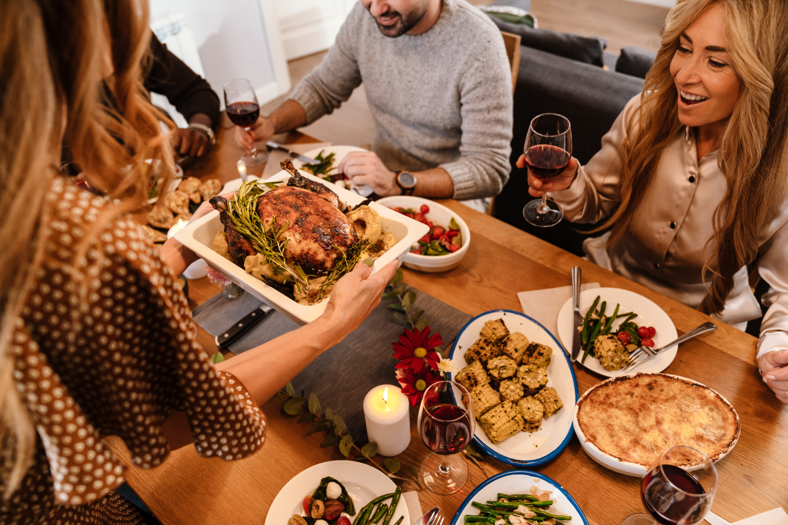 Multiracial happy friends eating turkey during thanksgiving dinner at home