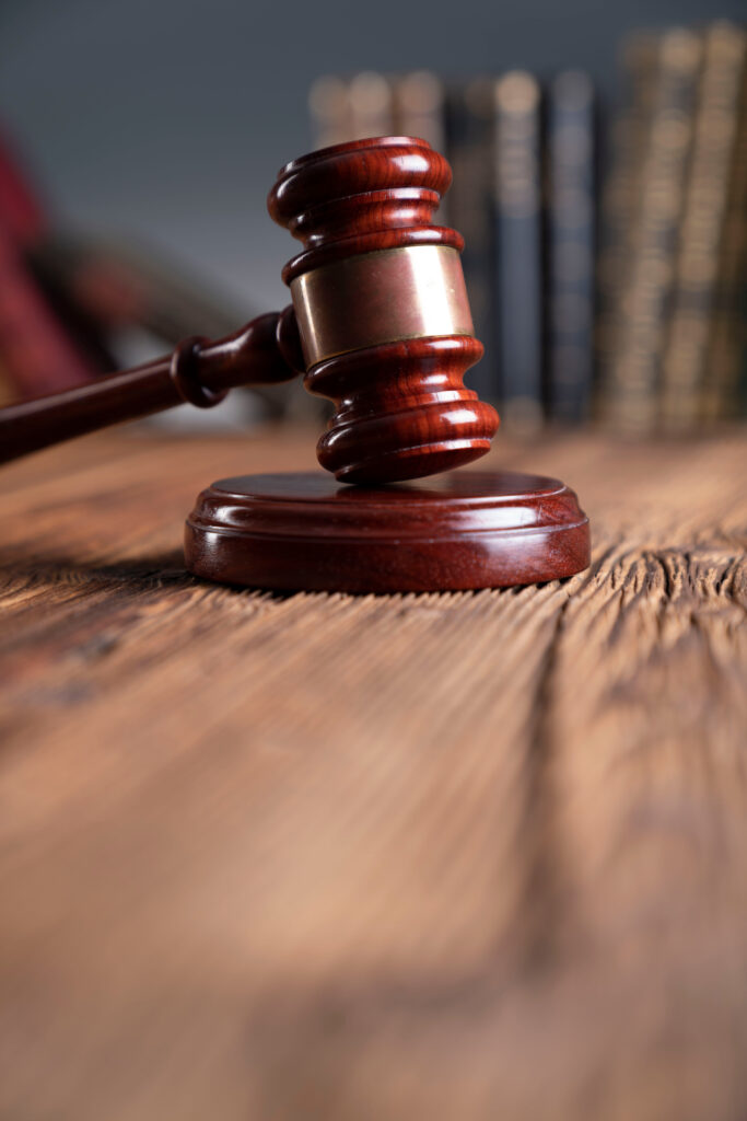 A wooden judge’s gavel rests on a block atop a rustic wooden table, with blurred books in the background, offering insight into justice through student perspectives.