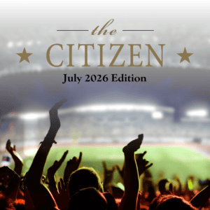 A cheering crowd at a stadium with "The Citizen, July 2026 Edition" emblazoned above in shimmering gold text, capturing the thrilling excitement of the moment as featured by The Citizen.