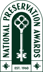 A logo featuring a large ornate key in the center, surrounded by the words “National Preservation Awards.” At the bottom, it says “EST. 1960” with a small star or decorative element on each side.