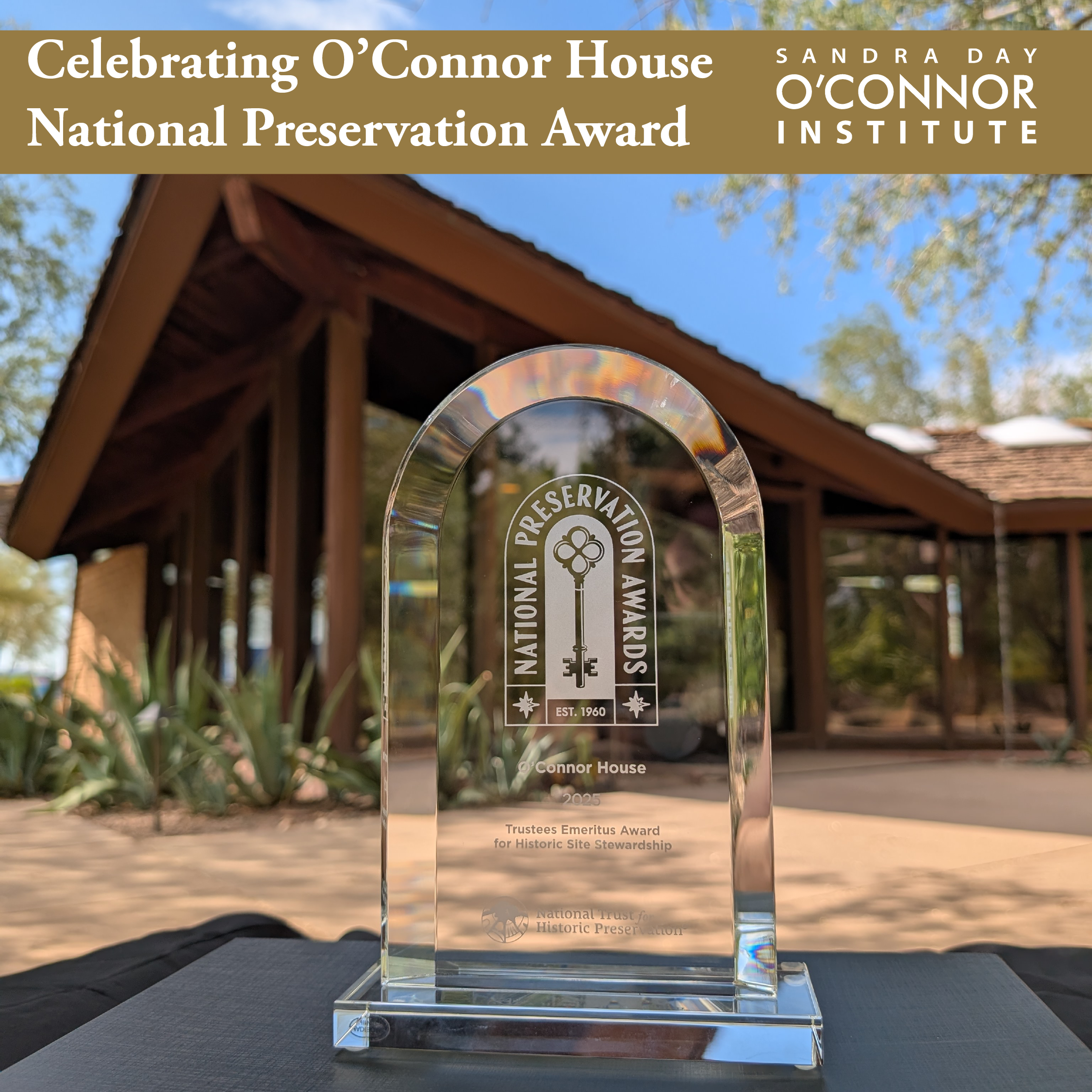 A glass National Preservation Award trophy sits on a table outdoors, with The Citizen and the O’Connor House framed by trees in the background. Text above reads “Celebrating O’Connor House National Preservation Award.”.