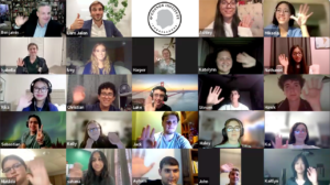 A virtual meeting with 20 people displayed in a grid. Each participant is smiling and waving at the camera. The backgrounds vary, with some showing rooms and others decorated walls. A circular logo at the top central tile reads "Oxford Institute US".