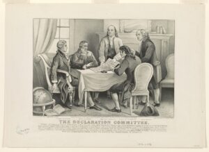 Five men in 18th-century attire gather around a table, examining a document. The room features a fireplace, globe labeled "America," and papers—capturing the spirit of Constitution Day and the drafting of the Declaration of Independence.