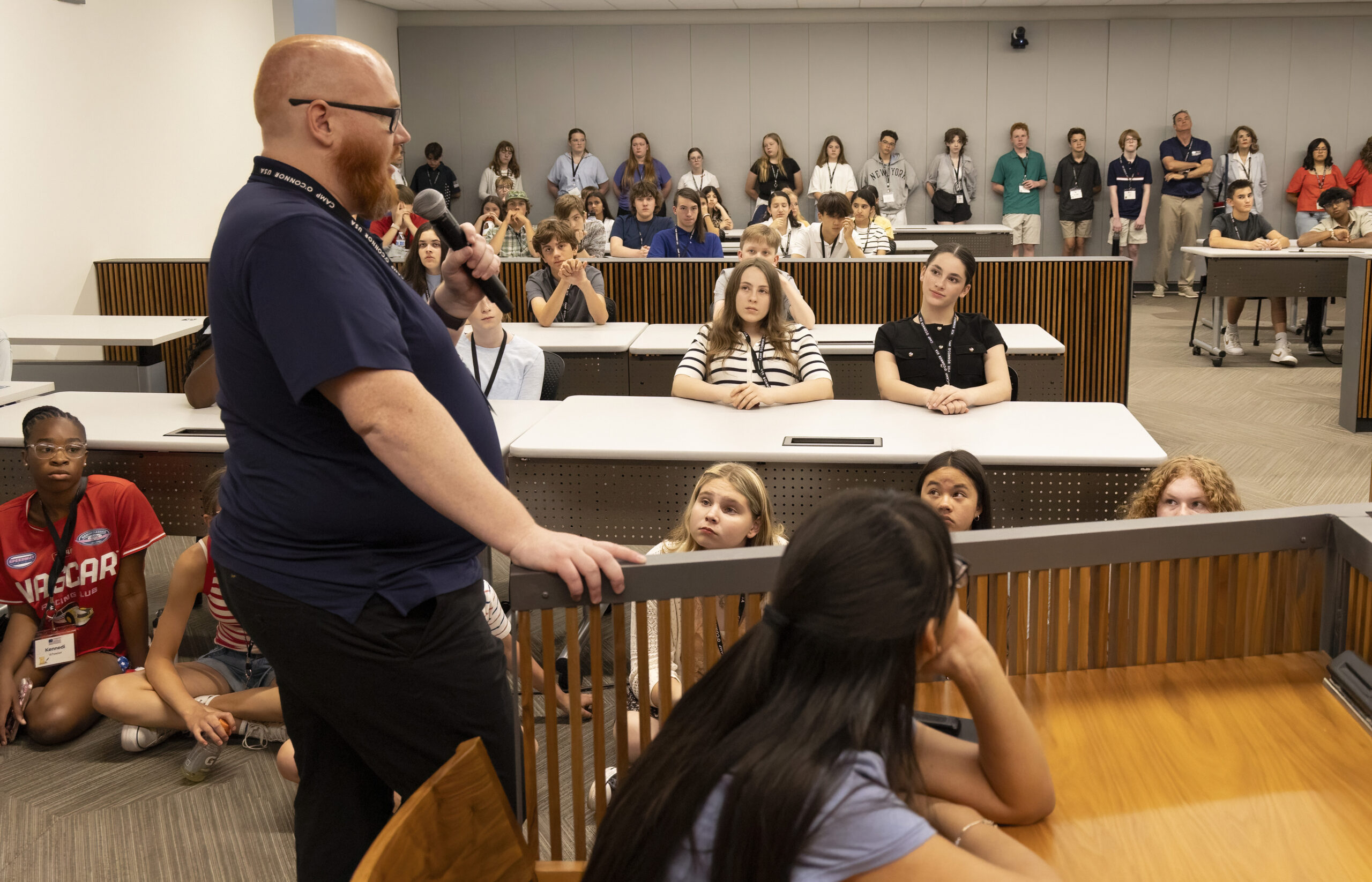 June 9, 2025 Camp SDO A bearded man speaks to a group of attentive students in a classroom, encouraging each young citizen as some sit at desks and others on the floor, all listening closely.