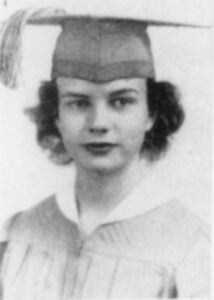 A young person wearing a graduation cap and gown. The image is a black and white portrait, showing them looking directly at the camera with a neutral expression.